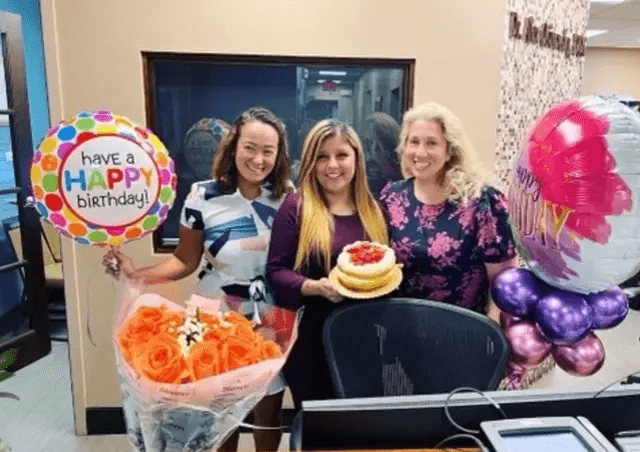 Tysons Dental team celebrating a birthday with cake, flowers, and balloons